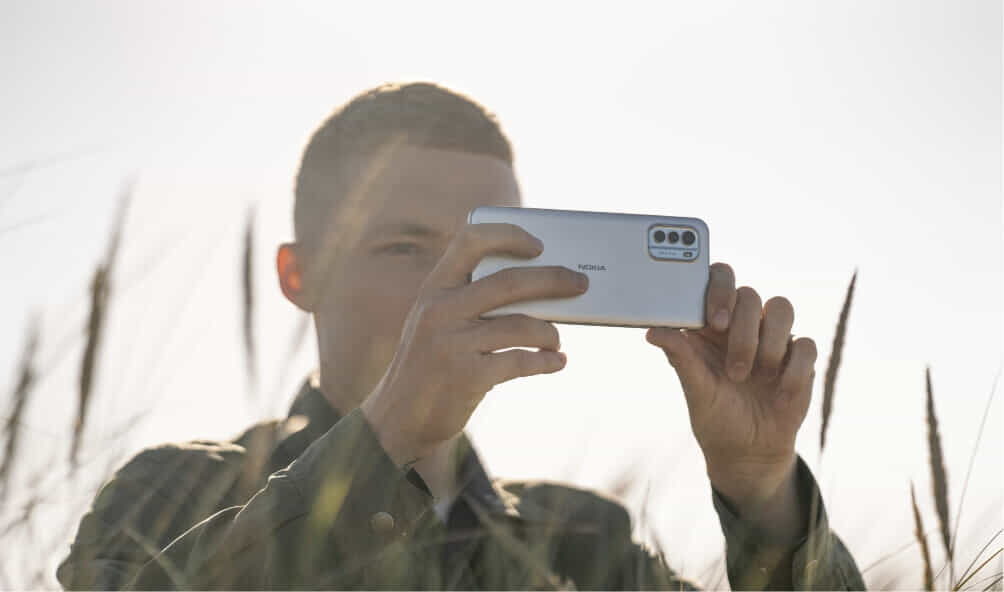 Man taking a photo on the beach using his G60 Nokia Smart Phone