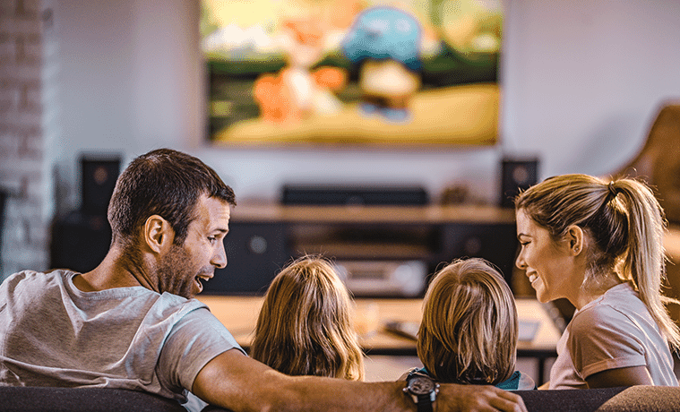 Rear view of a family watching TV on the sofa at home