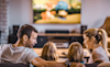 Rear view of a family watching TV on the sofa at home