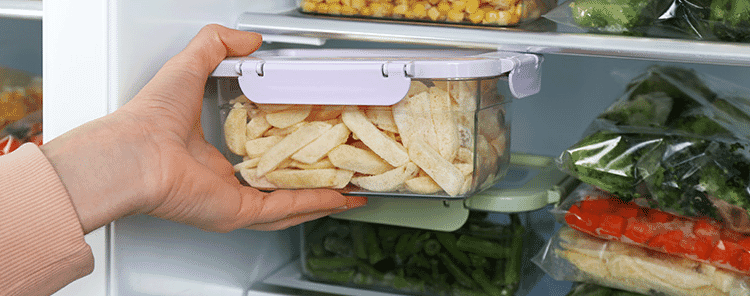 Closeup view of a woman taking a container of frozen potato chips from the fridge