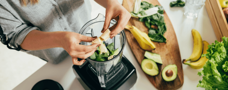 a woman making a morning smoothie in a blender 