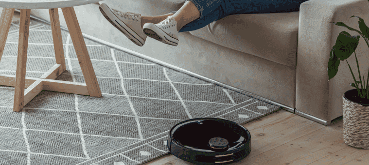 A lady sitting and relaxing while her robot vacuum cleans her living room 