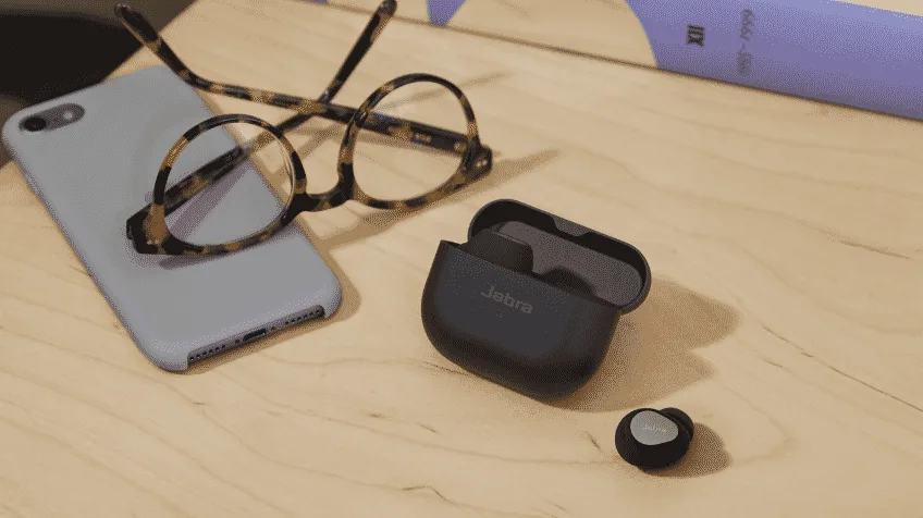 Jabra Elite 10 Earbuds sitting on a desk next to glasses and an iPhone