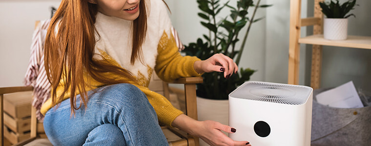 Woman turns on the air purifier in her living room