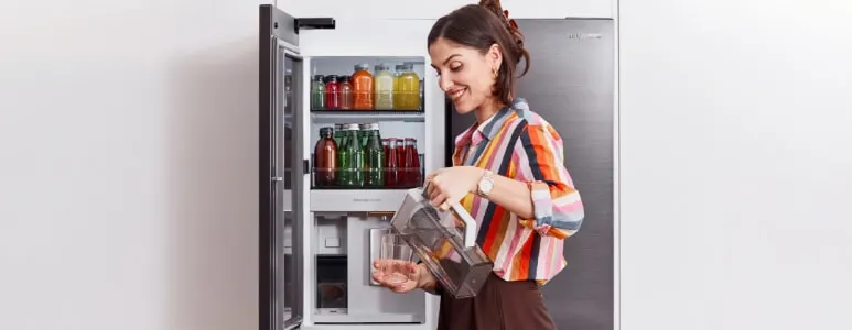A woman pours herself a drink from the Beverage centre using the Autofill Jug.