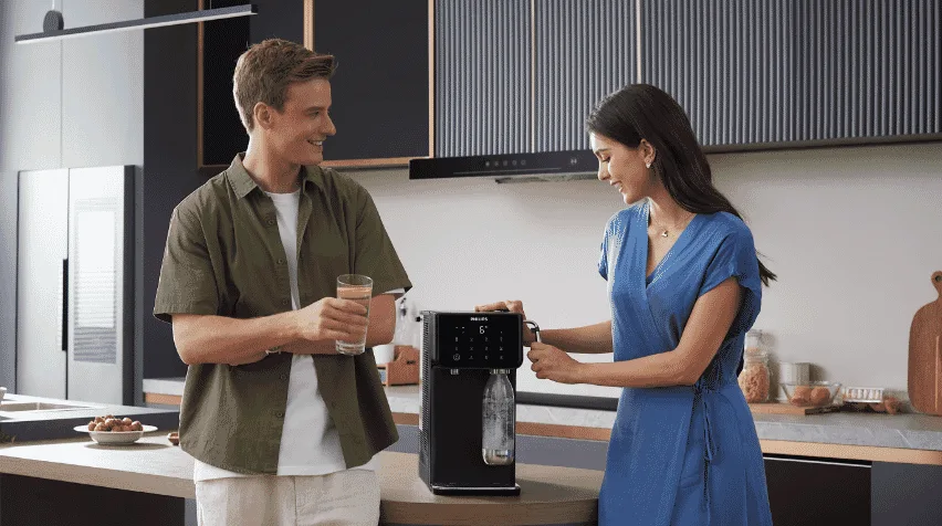 A man and a woman standing next to their Philips Sparkling water station