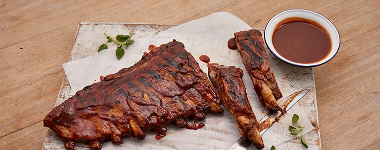 Pork ribs covered in sauce on a wooden table