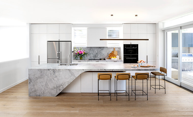 Contemporary open plan kitchen with white cabinetry and a central island bench topped with grey marble