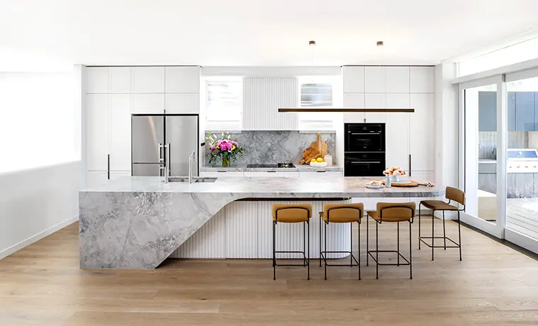Contemporary open plan kitchen with white cabinetry and a central island bench topped with grey marble