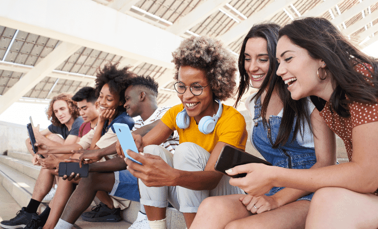 Teenagers sitting on some steps listening to music and looking at their phones