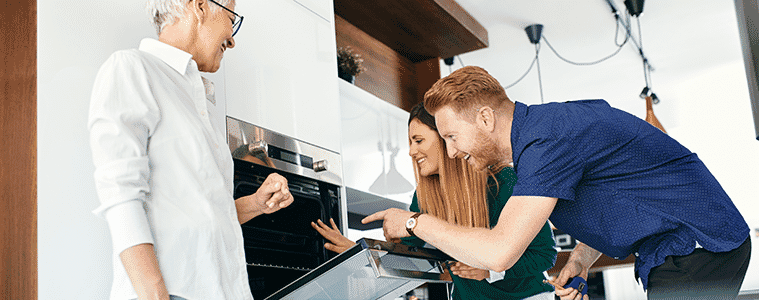 Couple open a wall oven to look inside when shopping for a new kitchen