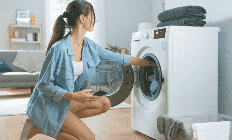 A woman puts laundry in her dryer