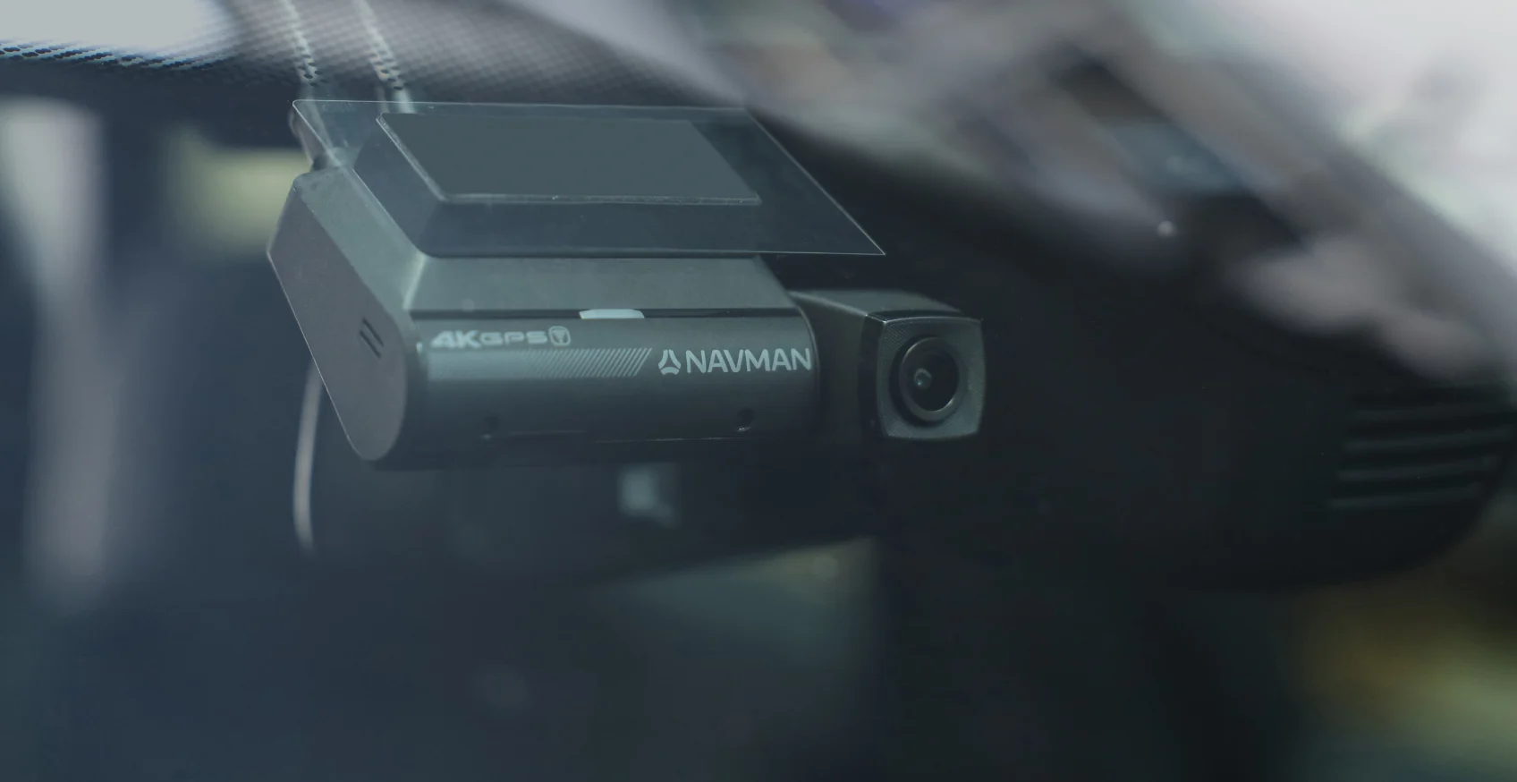 A Navman 4K Dash Cam attached to the windscreen of a car