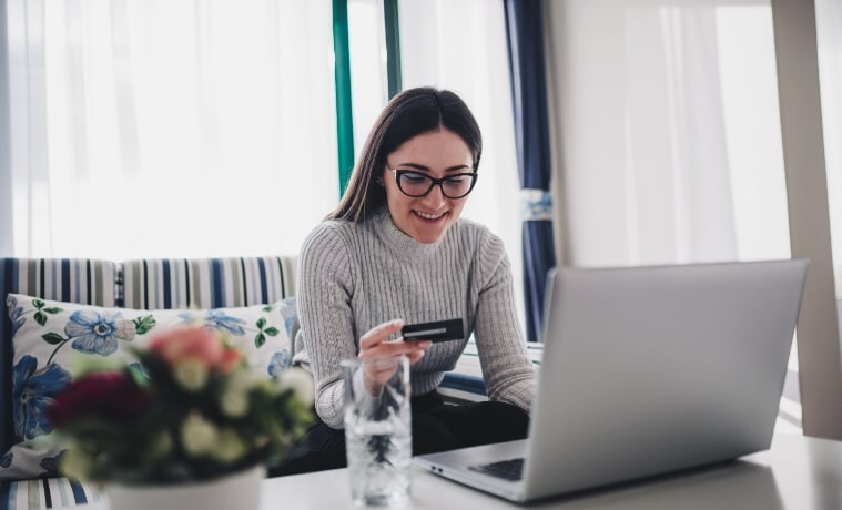 Excited woman purchasing products during the Black Friday Sale using her laptop and credit card