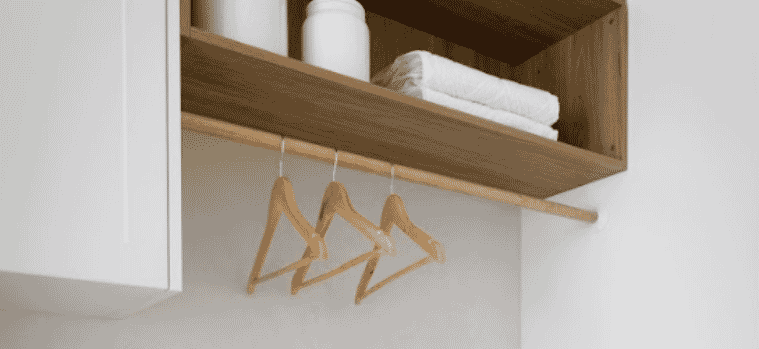Details of an open timber shelf builtin hanging rail above the bench and marblelook benchtop and splashback in a modern laundry 