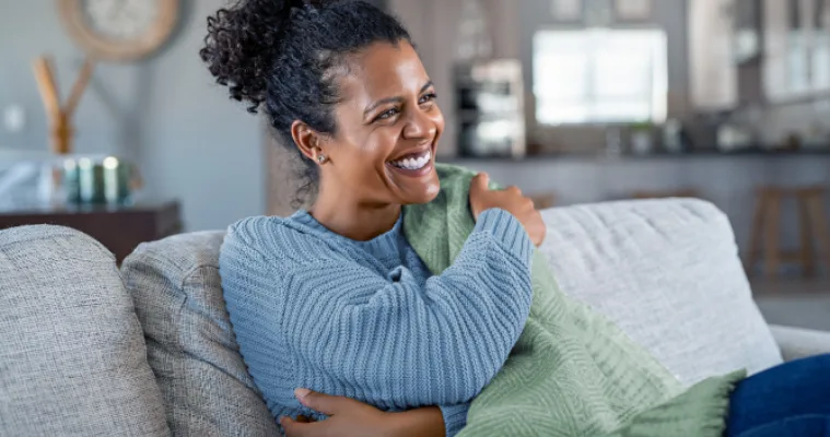 A woman on her couch underneath an electric blanket