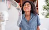 A smiling girl enjoys the cool breeze from a portable fan