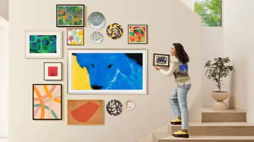 Woman hanging pictures around her The Frame TV