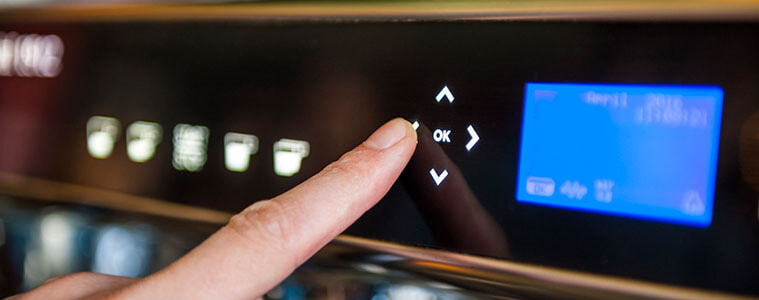 Closeup of a woman pushing a button on a digital panel on a coffee machine