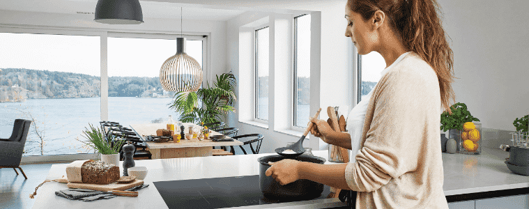 A woman preparing a meal on an induction cooktop in a beautiful modern home 