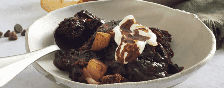 Oozy chocolate and pear selfsaucing pudding in a ceramic bowl with a silver spoon 