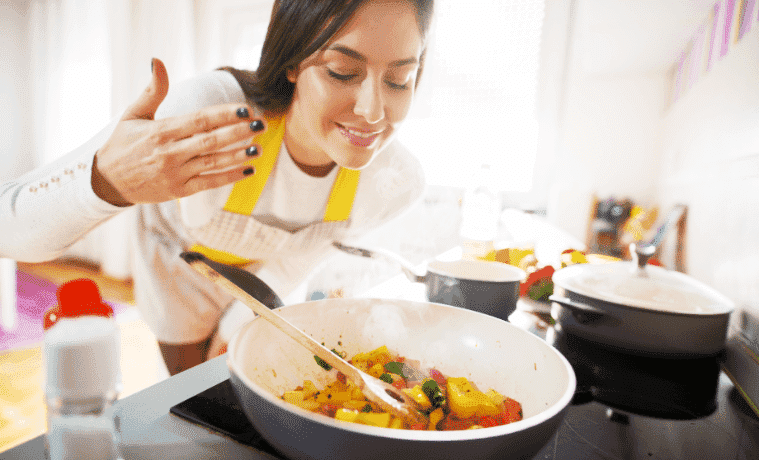 A woman smelling the aroma of her fresh and healthy breakfast cooking