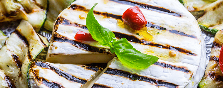 Grilled Brie cheese on a platter with grilled zucchini