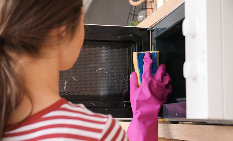A woman cleans her microwave door