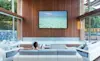 Woman watches a flat screen TV mounted on a living room wall 