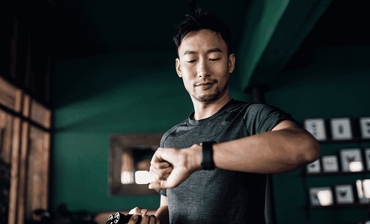 Active young man exercising at home using a fitness tracker to check his heart rate