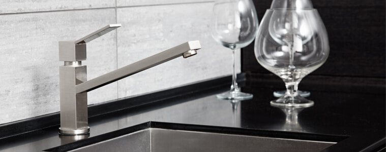 A brushed silver single lever mixer tap in a grey and black kitchen