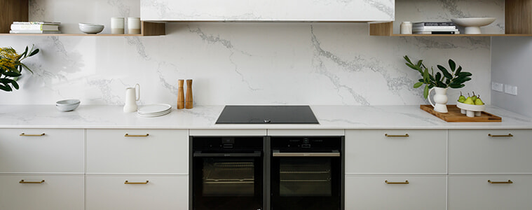 White modern kitchen cabinetry with integrated oven and brasscoloured handles