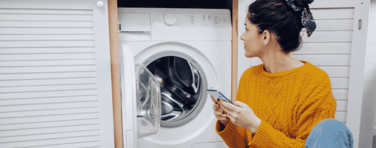 A woman uses her smartphone to control her washing machine