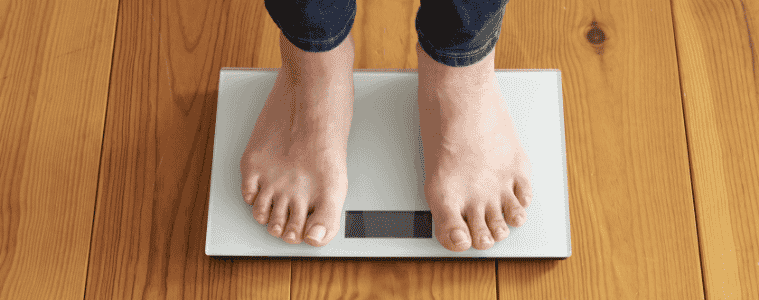 Womans feet on scales sitting on a wooden floor