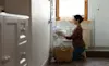A woman removes a freshly dried fluffy white towel from the dryer in her laundry room