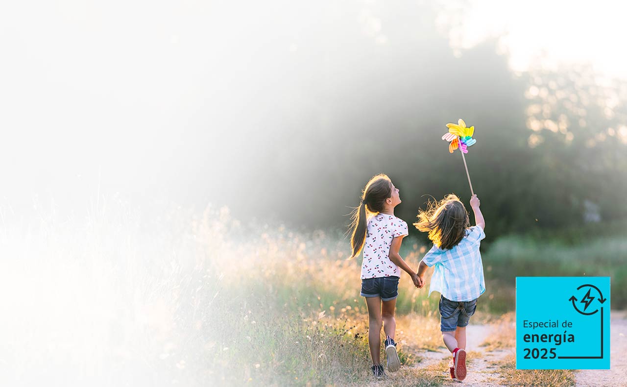 Foto de dos niñas corriendo por un campo verde y soleado, mientras una de ellas lleva una veleta de juguete en la mano.