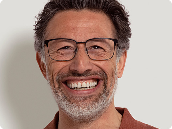 Man with a greying beard wearing thin, metal framed glasses