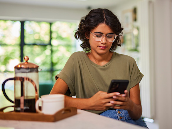 Girl browsing on a smart phone in a kitchen