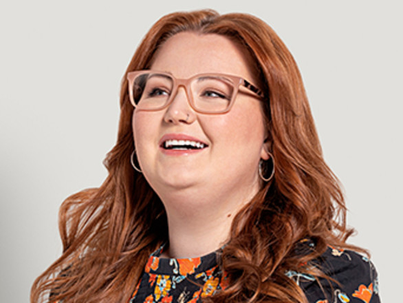 Woman with red hair wearing light pink glasses