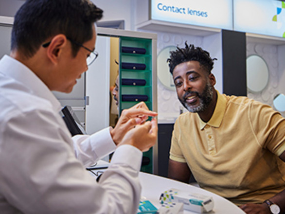 An optician demonstrating contact lenses to a customer