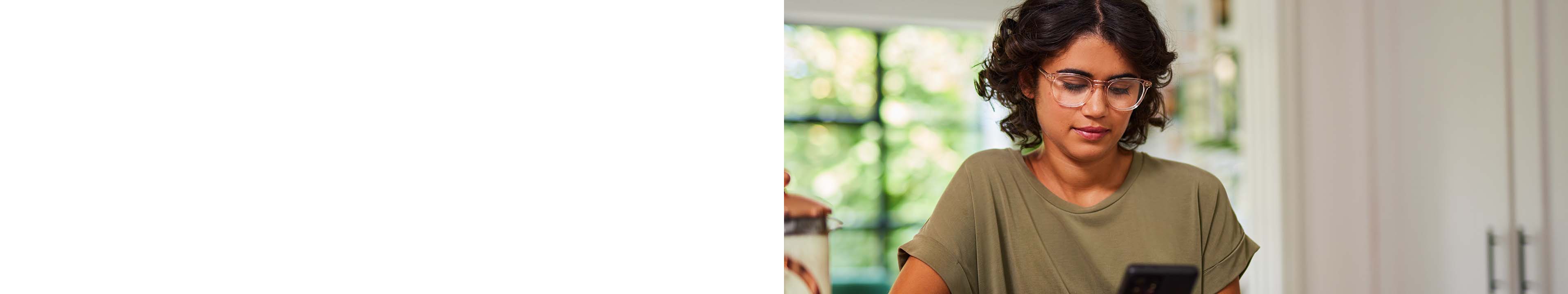 Young lady wearing pastel glasses looking at phone