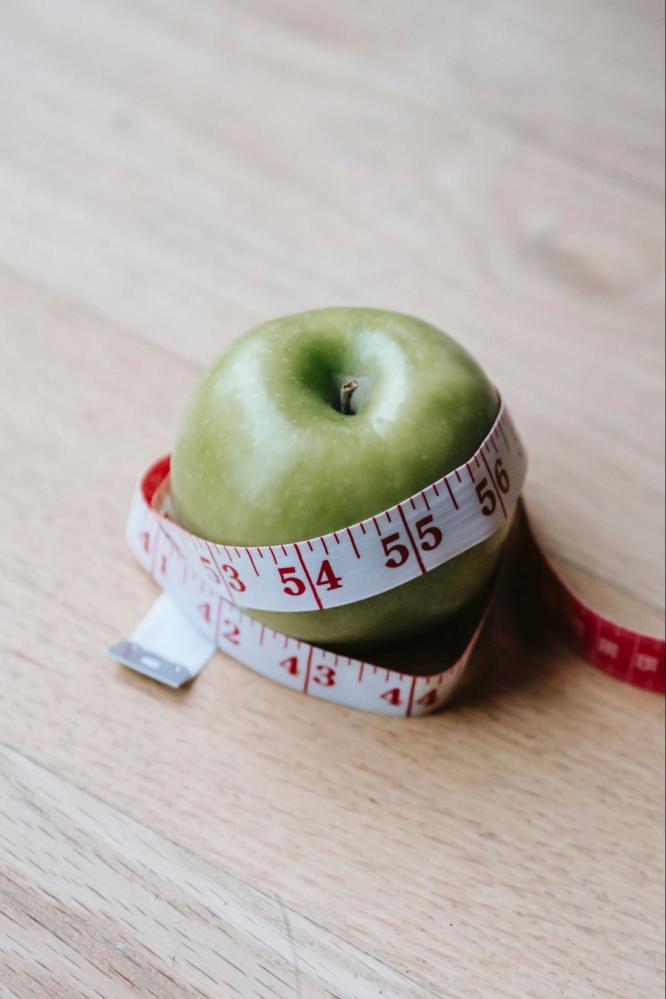 An apple with a measuring tape around it.