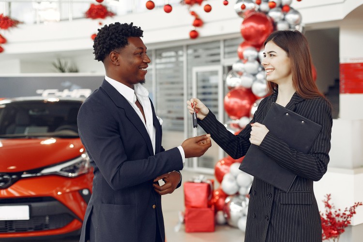 Person handing over keys to a new car after driver got car insurance coverage before purchasing their vehicle