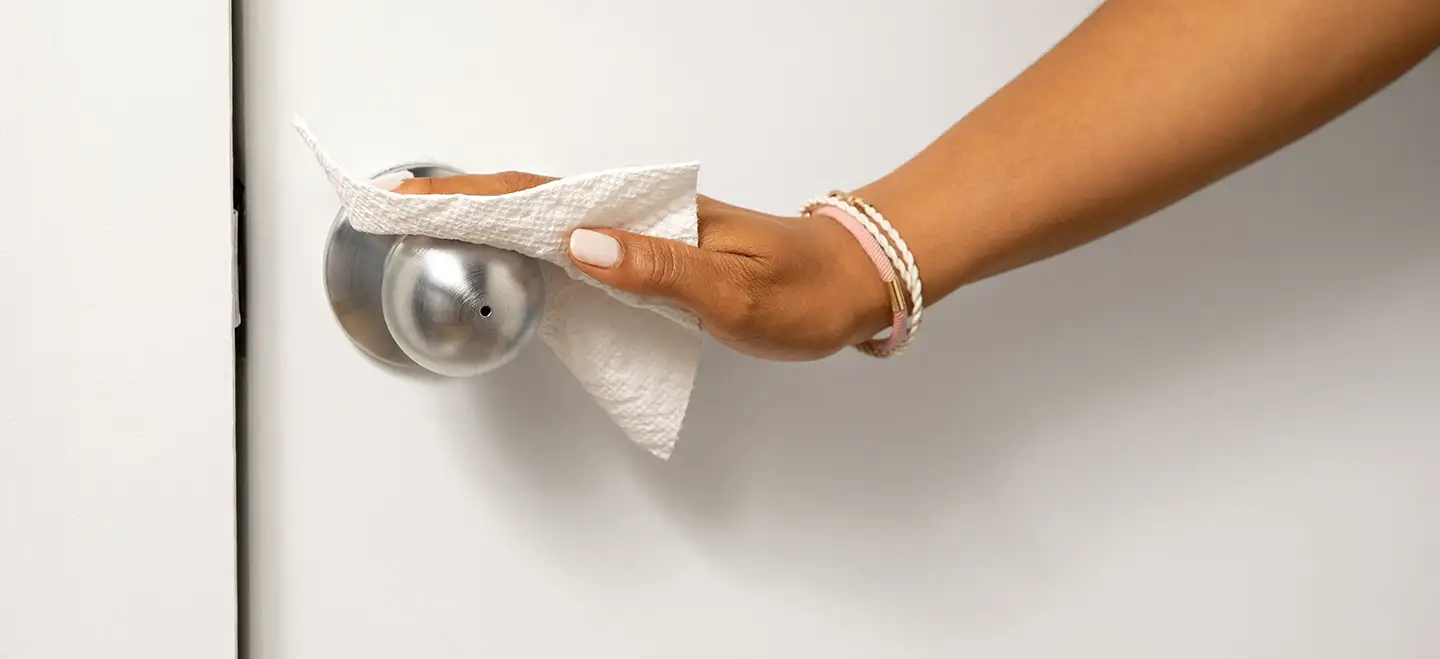 Woman cleaning steel doorknob with Bounty paper towel
