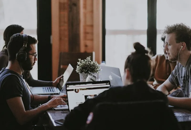 A development team working together on laptops at a conference table in an office.