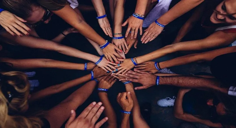A group of people in a huddle putting hands together.