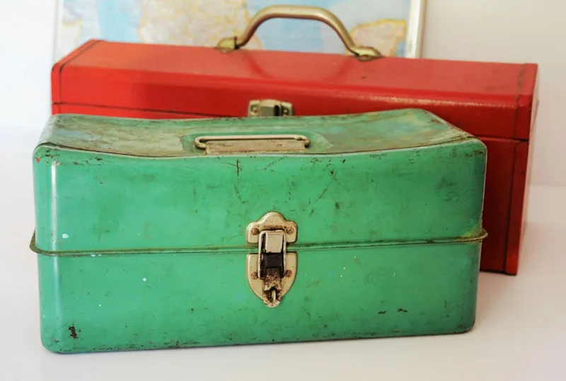 Two old metal toolboxes with wear and tear showing; one mint green in the foreground and the second red, in the background.