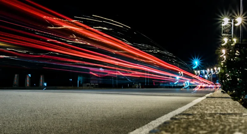 A city street at night with car lights streaming by.