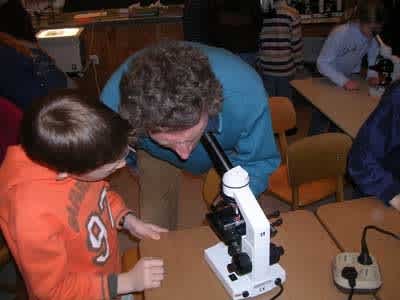 Ein Lehrer schaut durch ein Microskop