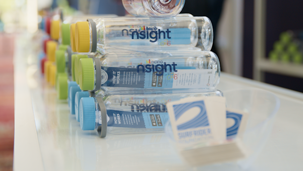 Rows of nSight 2026 reusable water bottles with colorful caps displayed at the registration table, alongside Surfrider Foundation stickers attendees used to personalize their bottles.